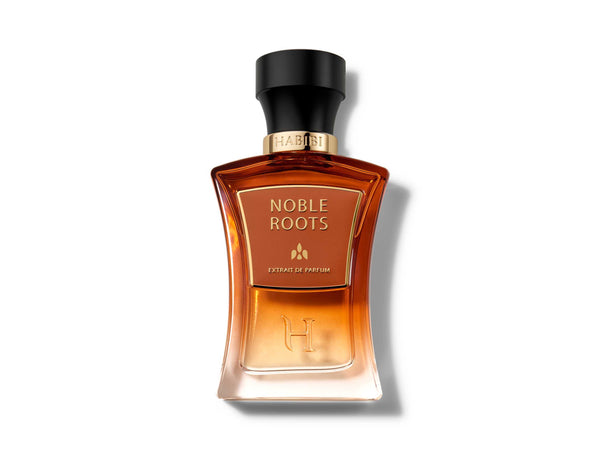 Noble Roots Extrait de Parfum by HABIBI New York, amber-red glass bottle with black cap resting on tan leather.